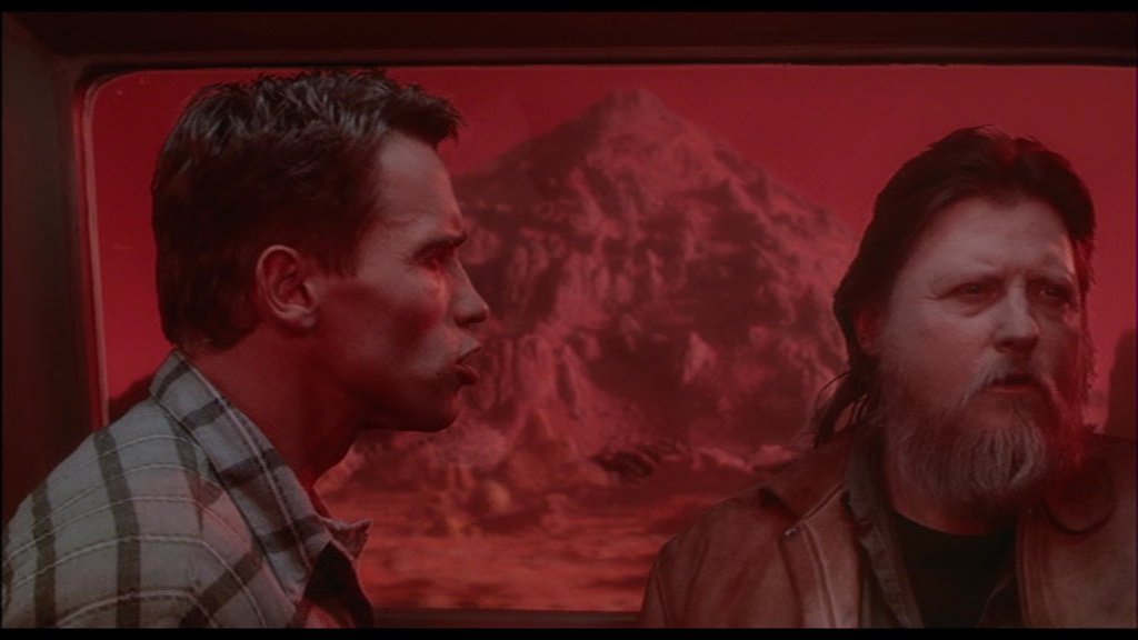 Mickey Jones e Arnol Schwarzenegger em O Vingador do Futuro